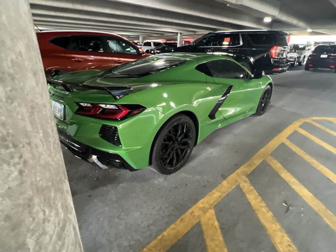 Rear three-quarter view of the green Corvette Stingray in an airport parking garage